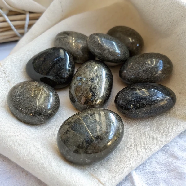 Natural nuummite stone from Greenland showing golden and blue iridescent flash against black background