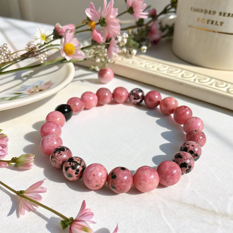 Rhodonite beaded bracelet showing multiple polished pink stones with black patterns